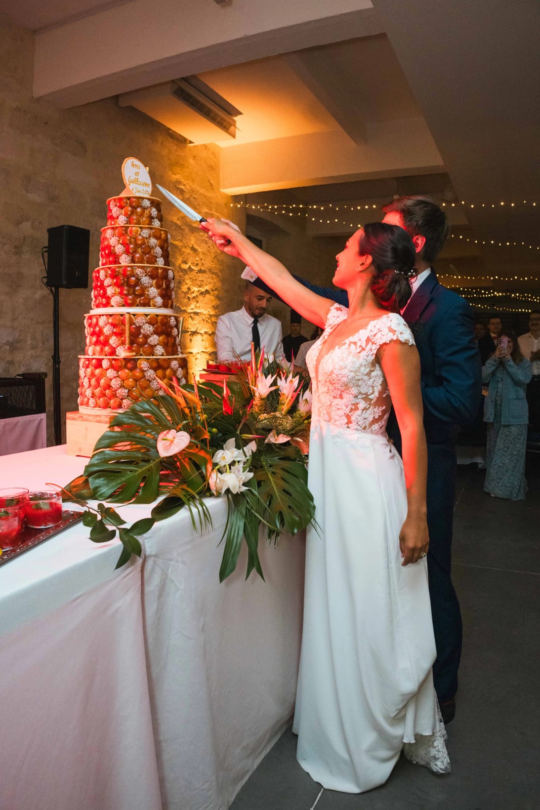 Ana, aidée de Guillaume, plante le couteau au sommet de la pièce montée de choux caramélisés, devant les invités, mariage au Domaine d'Orgival, par Jean-Baptiste Argyre (Jaysphotography)