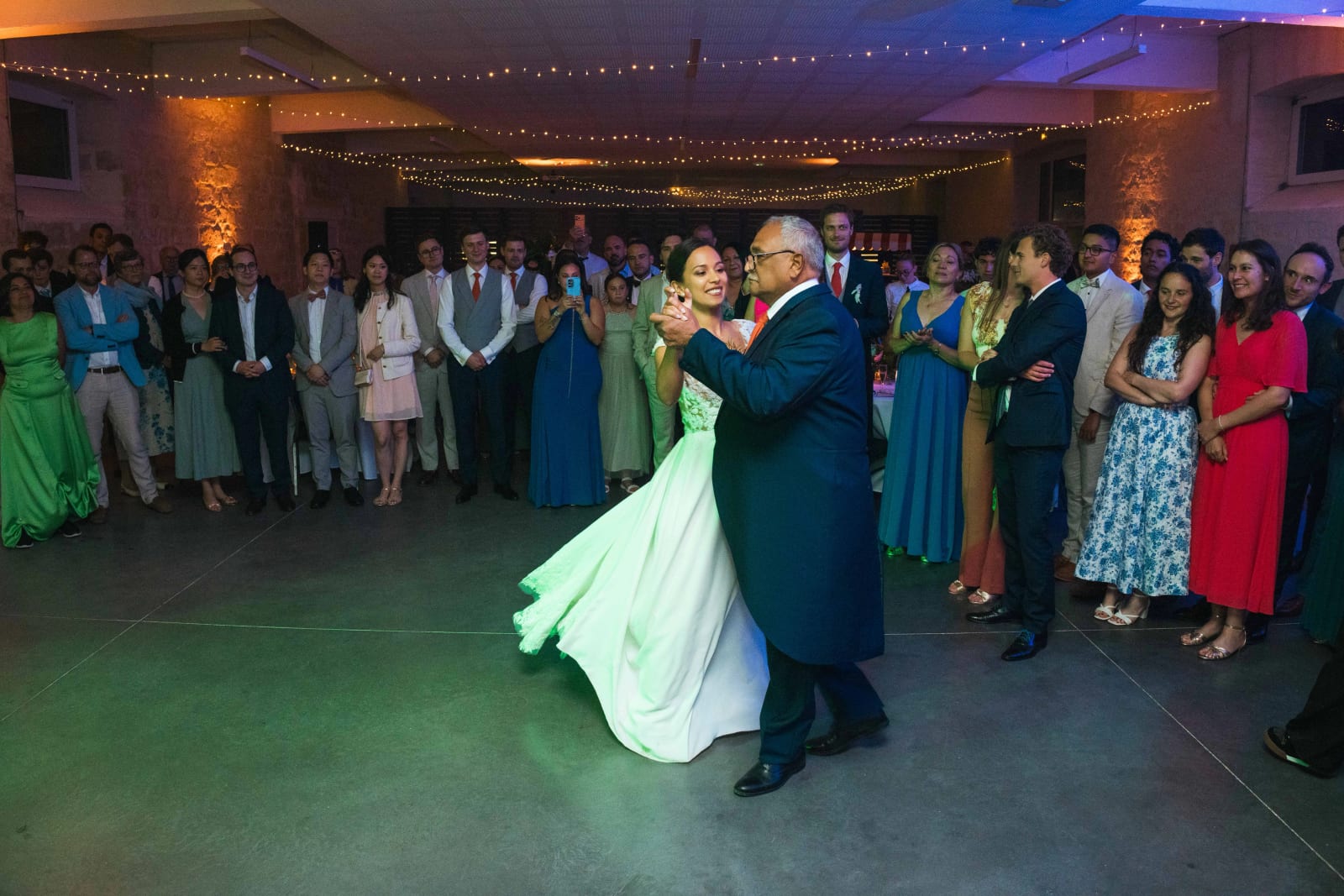 Ana ouvre le bal en dansant avec son papa au centre du cercle des invités, robe en mouvement sous les lumières vertes, mariage au Domaine d'Orgival, par Jean-Baptiste Argyre (Jaysphotography)