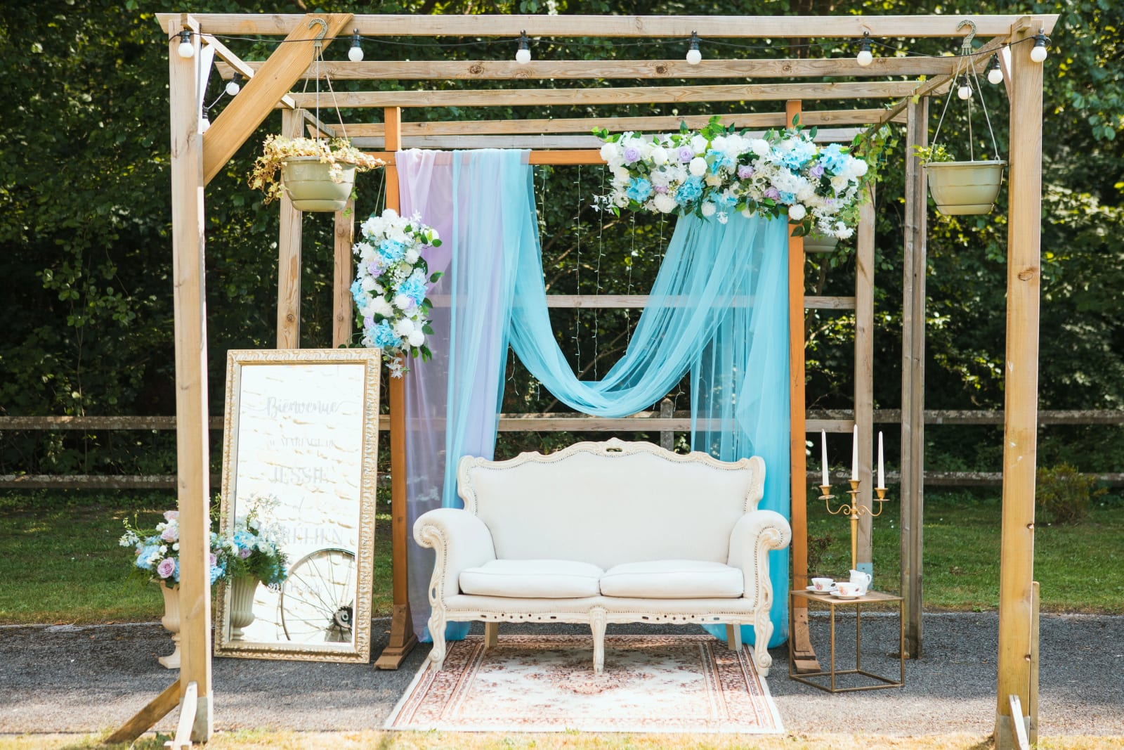 L'arche drapée de bleu ciel et son canapé vintage, coin photo de la réception, mariage au Domaine de l'Orangerie de Villette, par Jean-Baptiste Argyre (Jaysphotography)