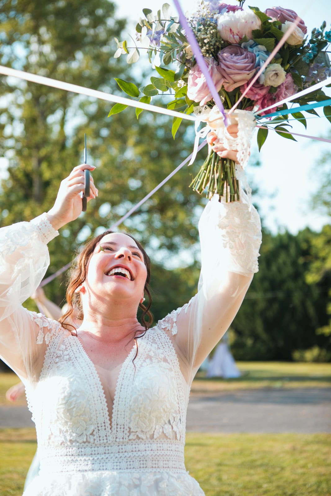 Jessie riant sous la ronde des rubans, le bouquet dans les airs, mariage au Domaine de l'Orangerie de Villette, par Jean-Baptiste Argyre (Jaysphotography)