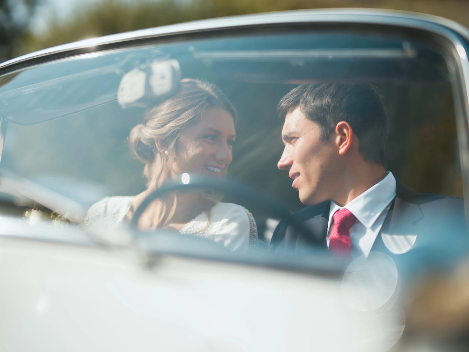 Les mariés rient assis dans la Caravelle, photographiés à travers le pare-brise, mariage au Domaine le Pommerieux, Buzancy, par Jean-Baptiste Argyre (Jaysphotography)
