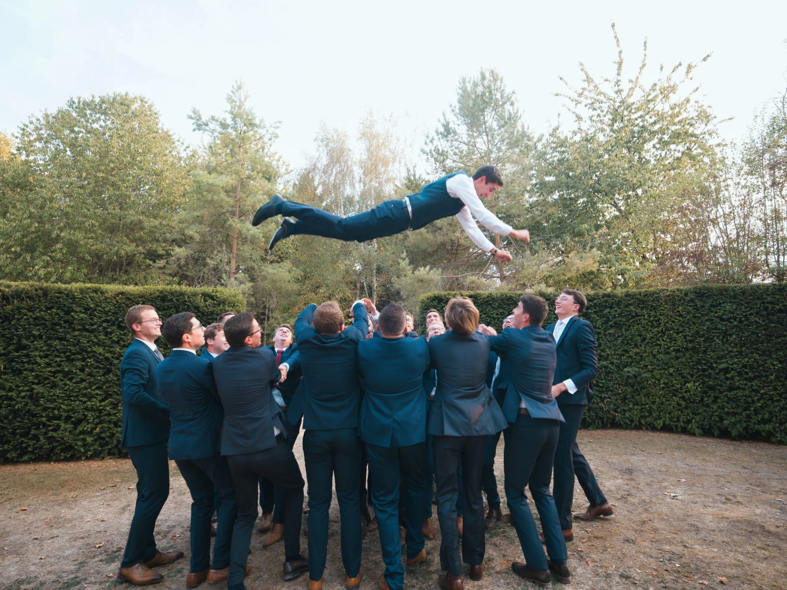Le marié lancé en l'air par ses amis en costume devant les haies du parc, mariage au Domaine le Pommerieux, Buzancy, par Jean-Baptiste Argyre (Jaysphotography)