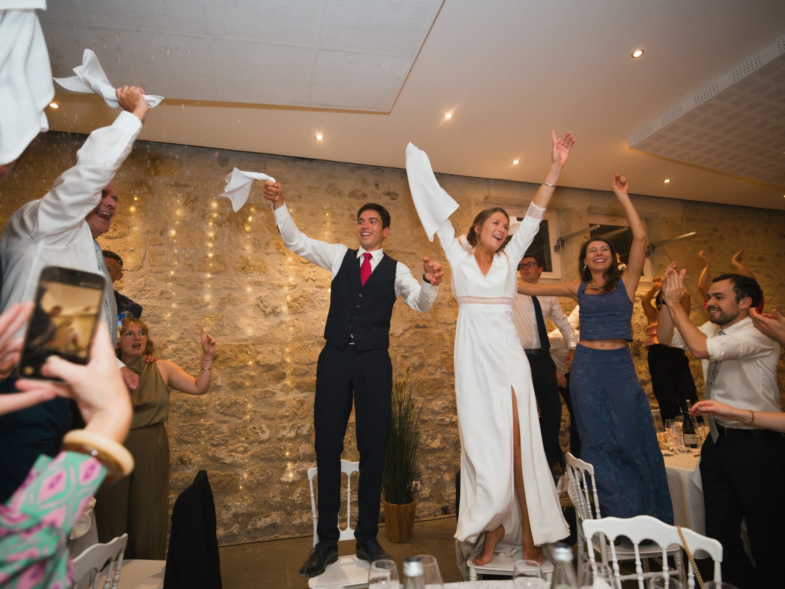 Les mariés debout sur leurs chaises font tourner leurs serviettes avec les invités, mariage au Domaine le Pommerieux, Buzancy, par Jean-Baptiste Argyre (Jaysphotography)