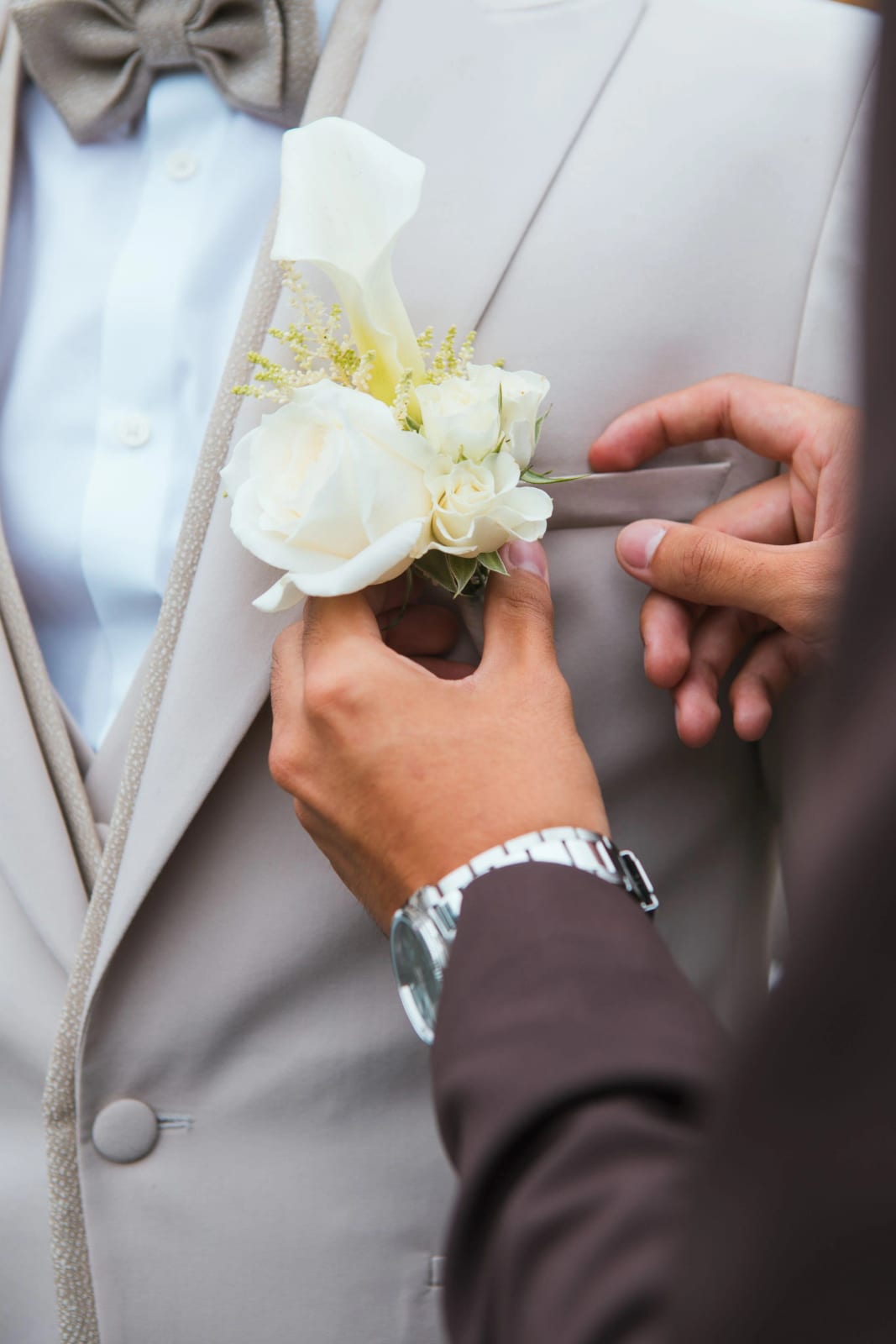 On épingle une boutonnière de roses blanches au revers du costume écru du marié, mariage à la Salle Georges Brassens, Villers-Saint-Paul, par Jean-Baptiste Argyre (Jaysphotography)