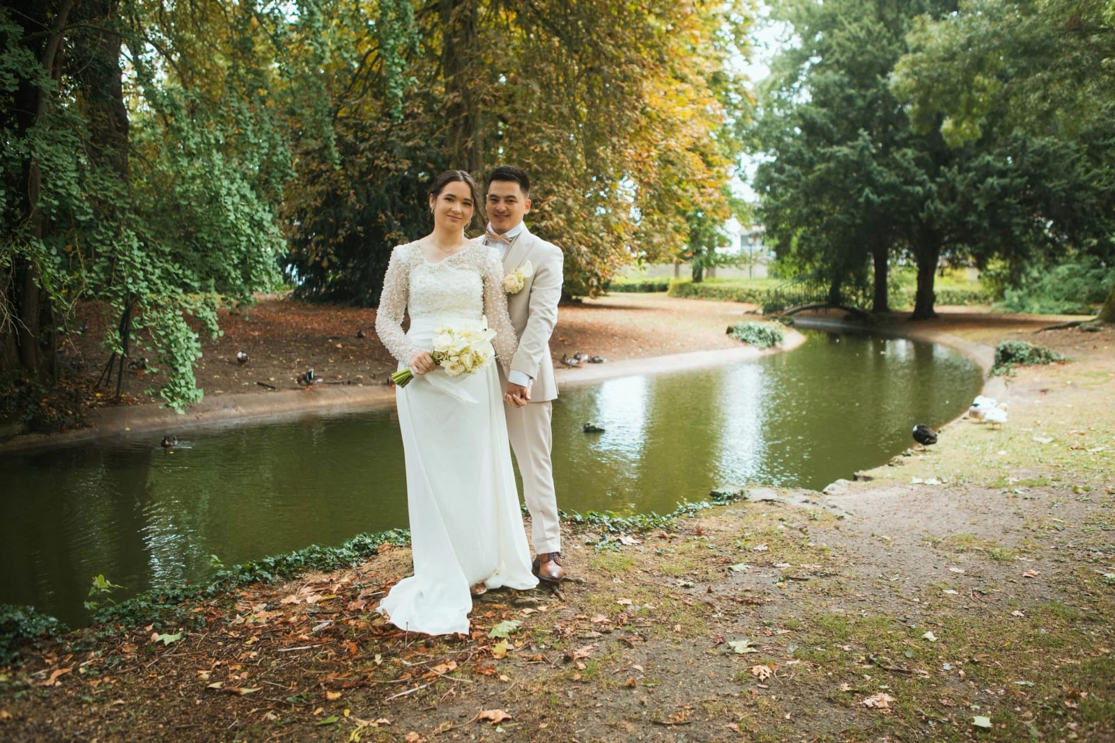 Les mariés au bord d'un bassin du parc du Château de Compiègne, arbres qui commencent à roussir, mariage à la Salle Georges Brassens, Villers-Saint-Paul, par Jean-Baptiste Argyre (Jaysphotography)
