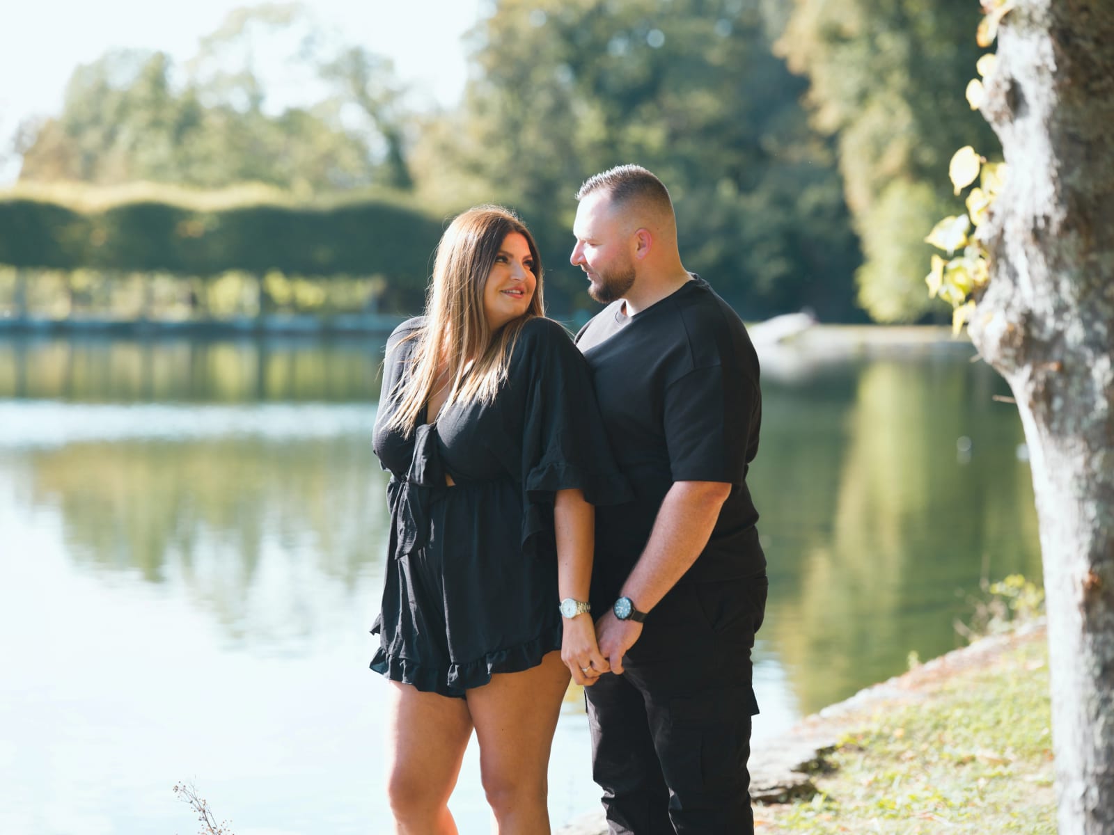Le couple debout au bord d'un canal du Domaine de Villarceaux, l'eau calme reflète les arbres et une haie taillée, mariage au Domaine de Villarceaux, Chaussy (Val-d'Oise), par Jean-Baptiste Argyre (Jaysphotography)
