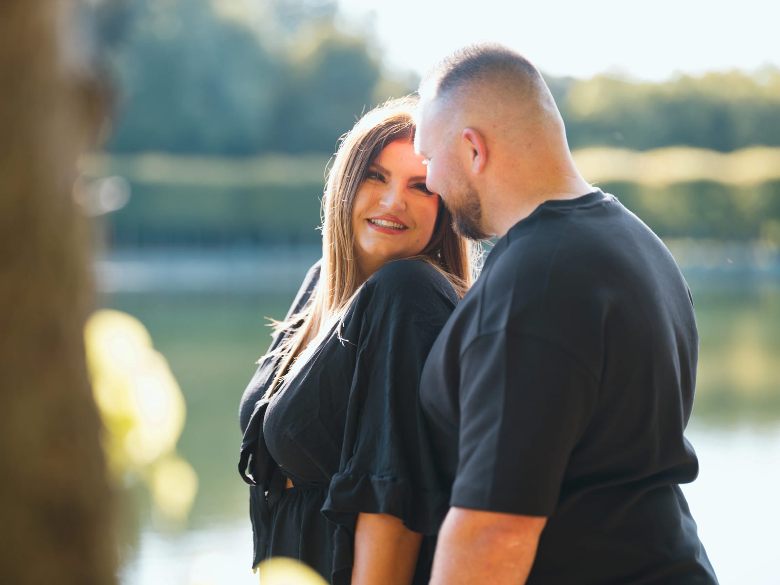 Portrait serré de Laurena et Anthony au bord de l'eau, pris à travers un tronc d'arbre, il pose son front contre sa tempe, mariage au Domaine de Villarceaux, Chaussy (Val-d'Oise), par Jean-Baptiste Argyre (Jaysphotography)