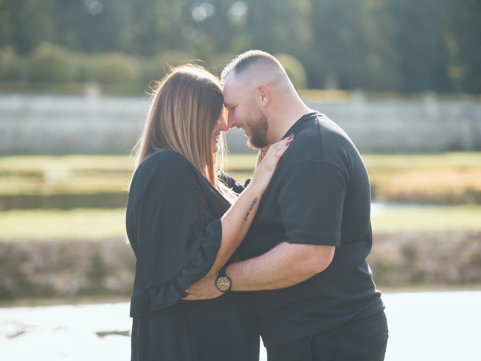 Le couple front contre front au soleil devant un canal et un mur de pierre, la main de Laurena sur la poitrine d'Anthony, mariage au Domaine de Villarceaux, Chaussy (Val-d'Oise), par Jean-Baptiste Argyre (Jaysphotography)