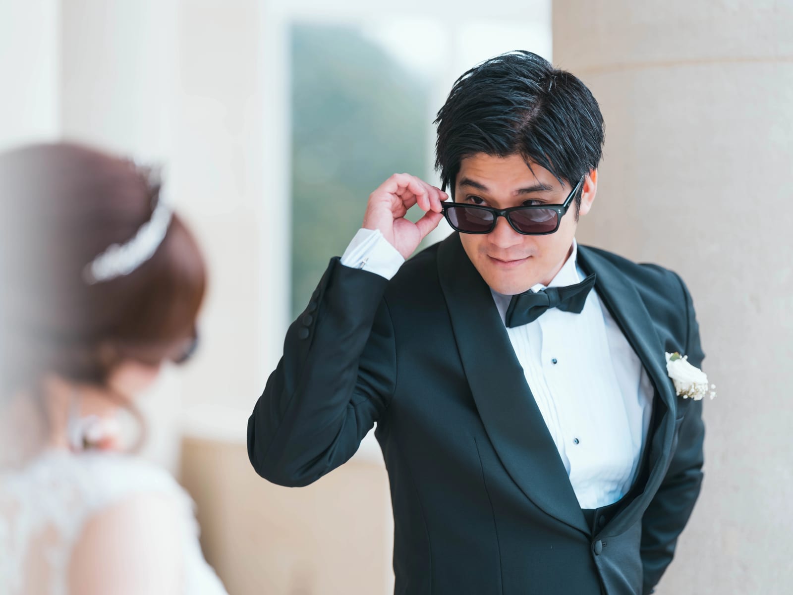 Le marié en smoking ajuste ses lunettes de soleil, la mariée floue au premier plan, mariage au Château Mont Royal, par Jean-Baptiste Argyre (Jaysphotography)