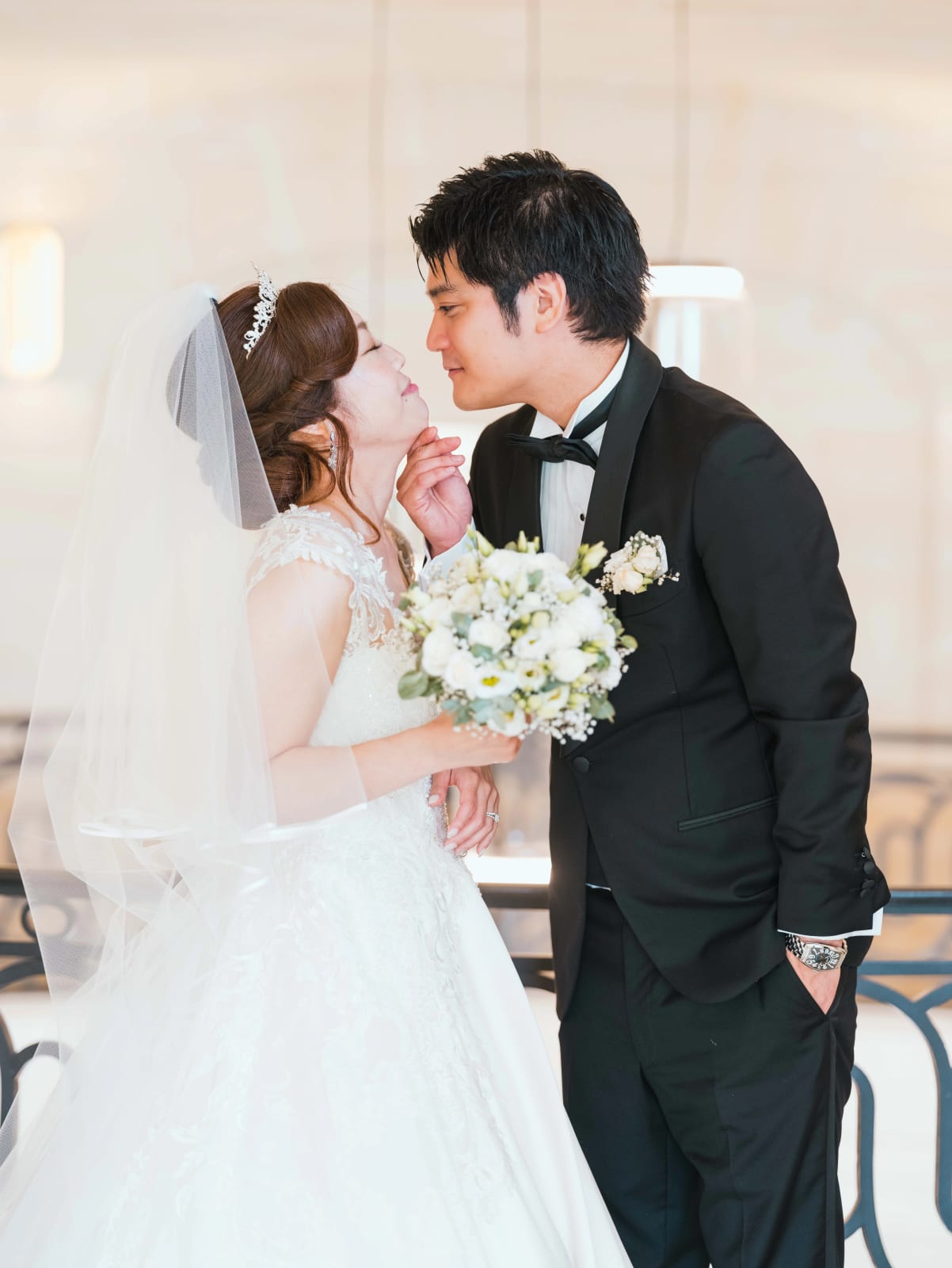 Le marié relève le menton de la mariée voilée, bouquet de fleurs blanches et gypsophile, mariage au Château Mont Royal, par Jean-Baptiste Argyre (Jaysphotography)