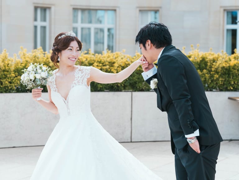 Baisemain du marié à la mariée qui rit, sur la terrasse de pierre bordée de haies