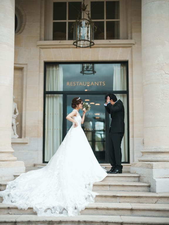 The couple at the top of the stone steps of the château entrance, the long train flowing down