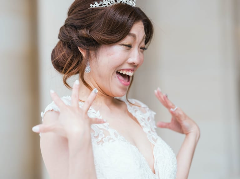 The bride bursts into laughter in her lace gown and tiara during an elopement at a French château