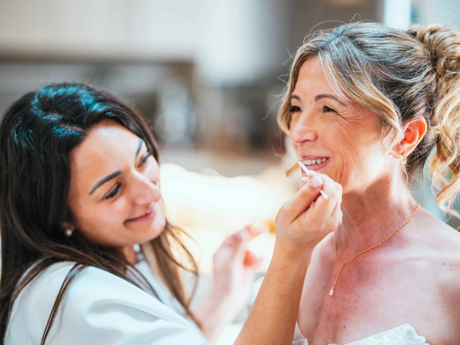 Fou rire entre Lydia et la maquilleuse au moment de la pose du rouge à lèvres, mariage au Domaine la Ferme du Roy, par Jean-Baptiste Argyre (Jaysphotography)