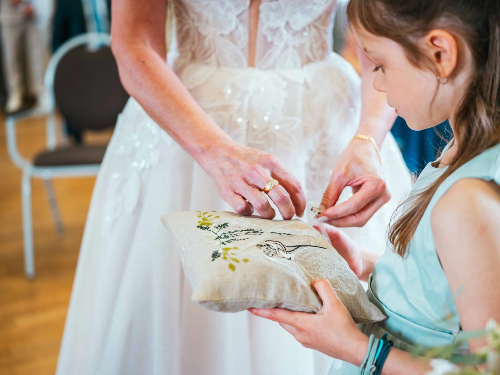 Une fillette tend le coussin d'alliances brodé à Lydia pendant la cérémonie, mariage au Domaine la Ferme du Roy, par Jean-Baptiste Argyre (Jaysphotography)