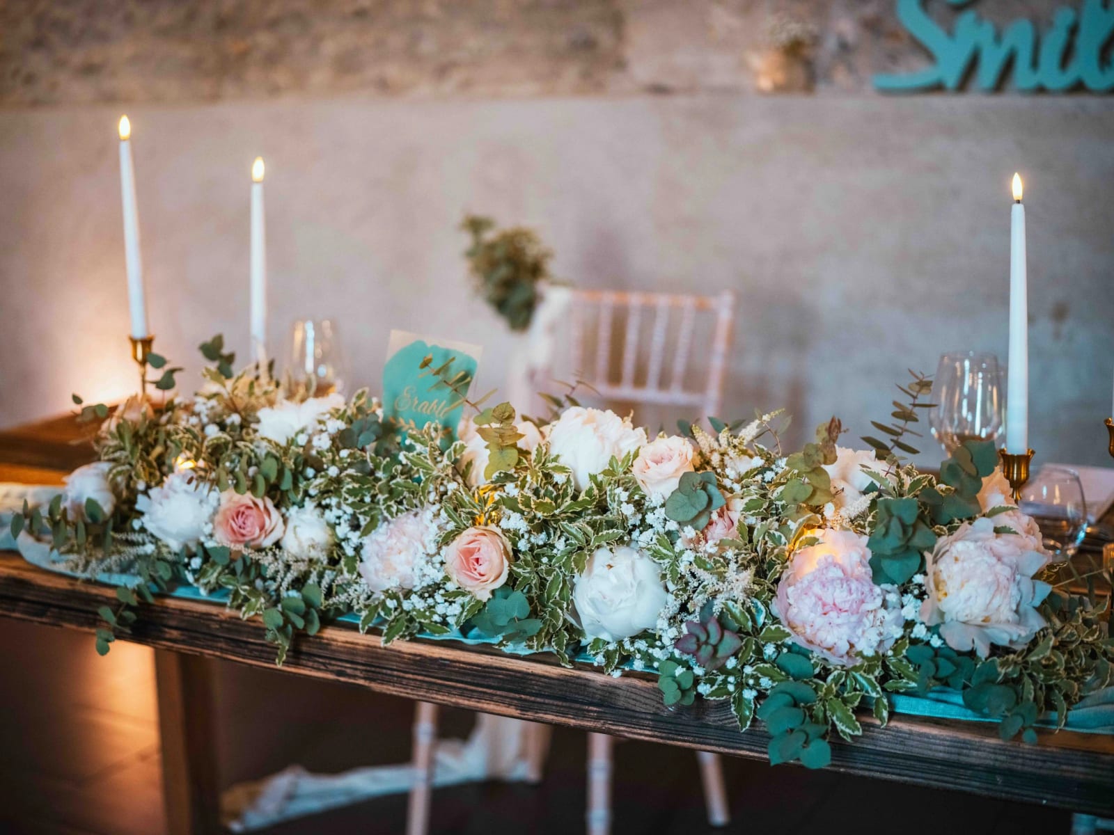 La table d'honneur et son chemin de pivoines roses et blanches, roses et eucalyptus, aux bougies, mariage au Domaine la Ferme du Roy, par Jean-Baptiste Argyre (Jaysphotography)