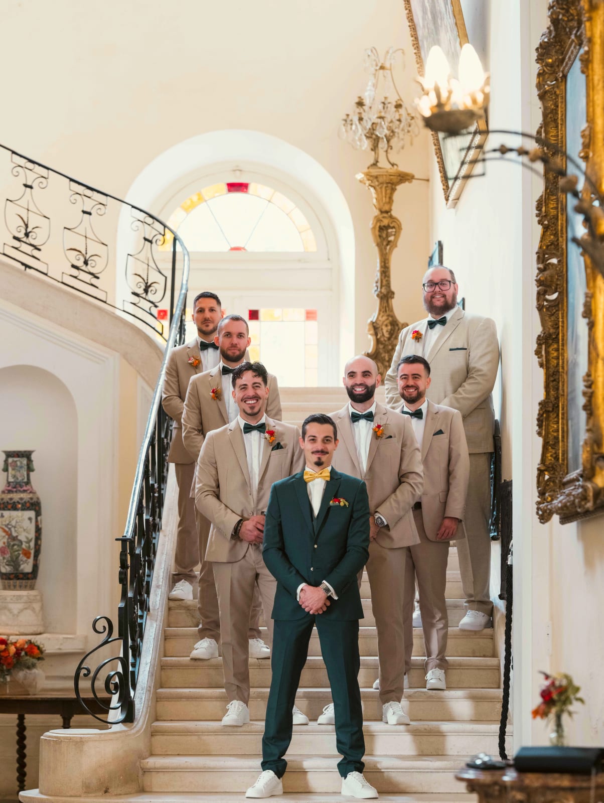 Le marié en costume vert et ses garçons d'honneur en costumes beige alignés sur le grand escalier de l'Abbaye de Longpont, mariage à l'Abbaye de Longpont, par Jean-Baptiste Argyre (Jaysphotography)