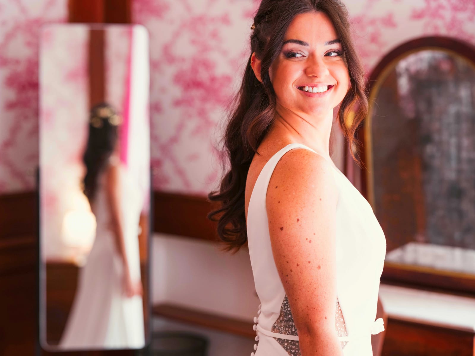 La mariée se retourne en souriant, dos de la robe boutonné et empiècements scintillants, son reflet dans un miroir, mariage à l'Abbaye de Longpont, par Jean-Baptiste Argyre (Jaysphotography)