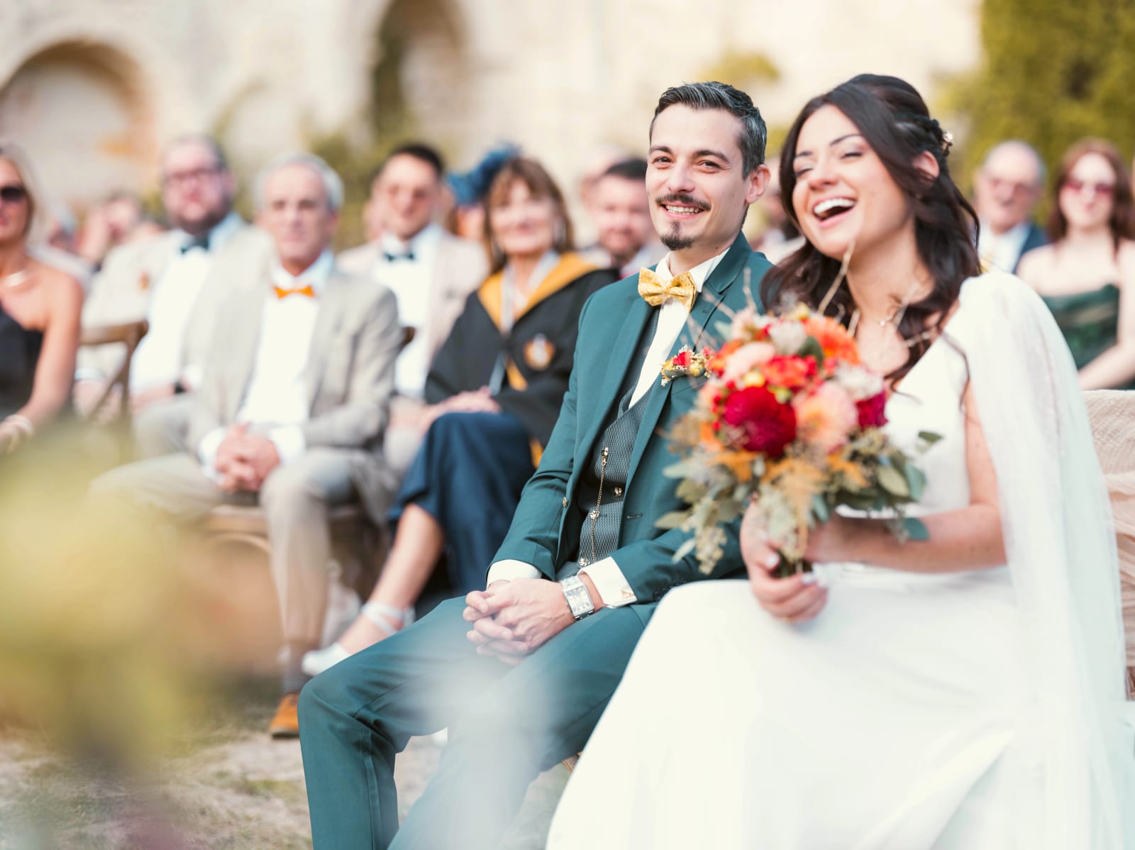 Les mariés rient pendant la cérémonie laïque, le marié en costume vert et nœud papillon moutarde, mariage à l'Abbaye de Longpont, par Jean-Baptiste Argyre (Jaysphotography)