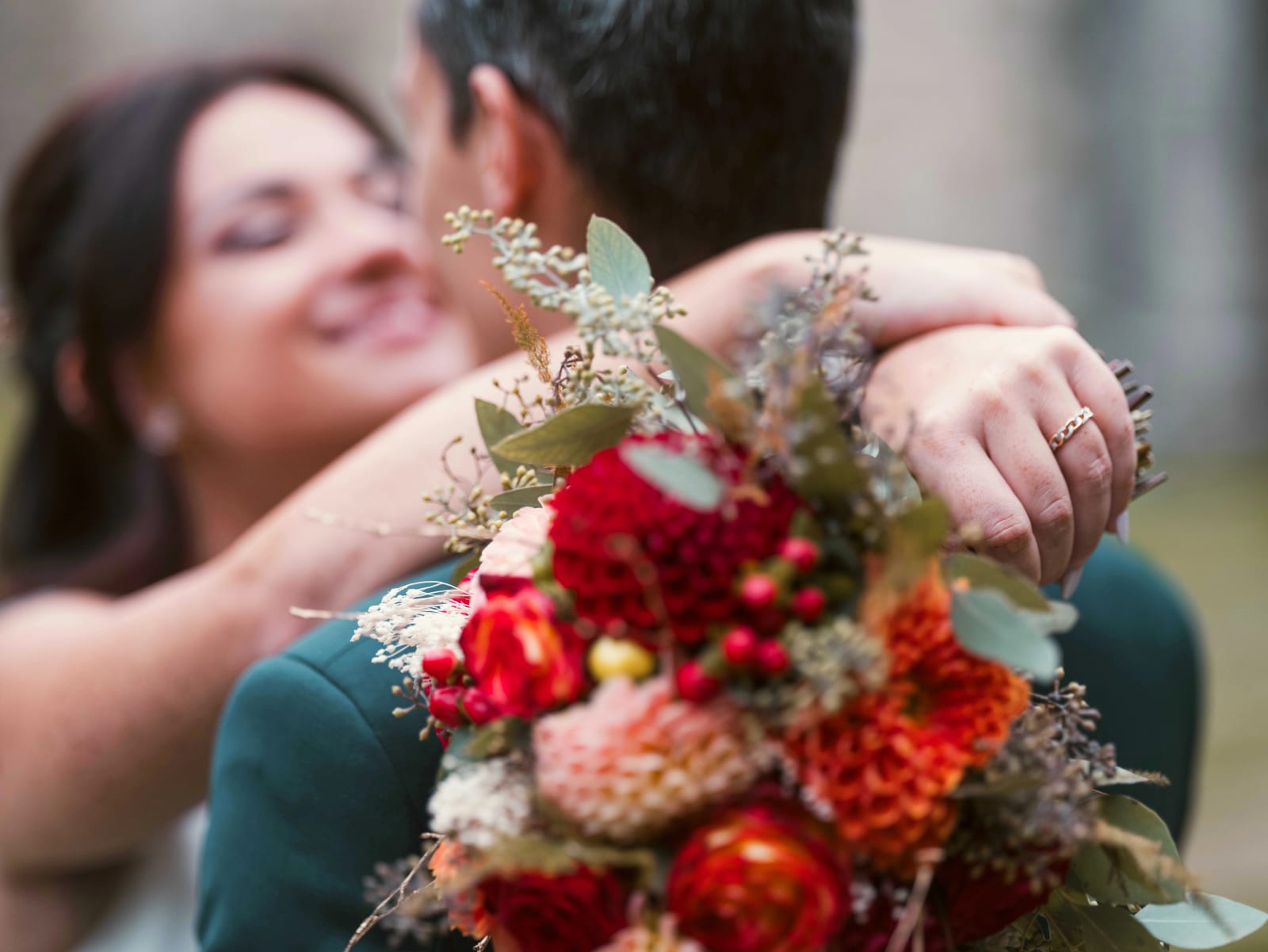 Gros plan sur l'alliance de la mariée, main sur la nuque du marié, bouquet de dahlias au premier plan, mariage à l'Abbaye de Longpont, par Jean-Baptiste Argyre (Jaysphotography)