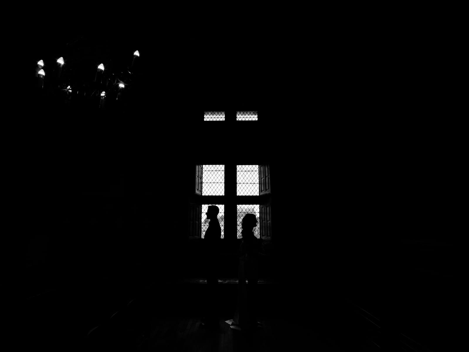 Silhouettes en contre-jour devant la fenêtre à croisillons d'un salon du Château de Moliens, en noir et blanc, mariage au Château de Moliens, par Jean-Baptiste Argyre (Jaysphotography)