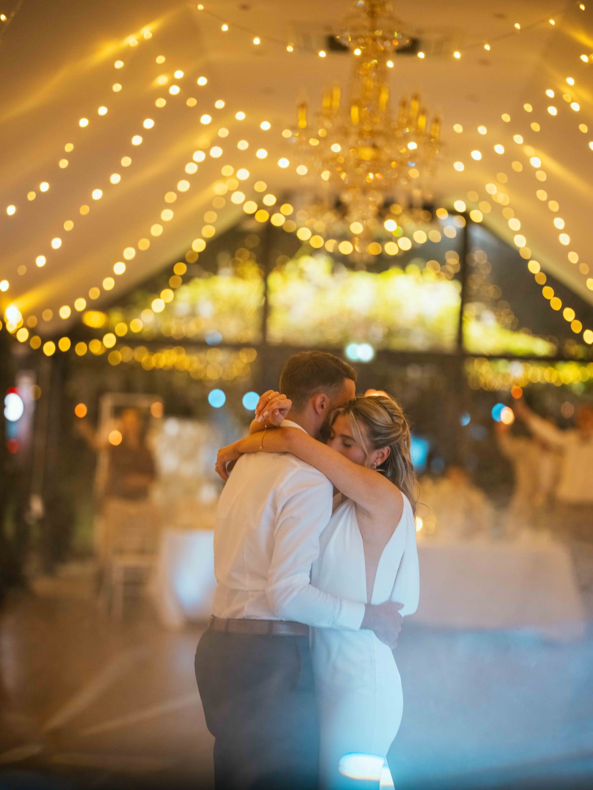 Mathilde et Paul enlacés au centre de la piste pour leur ouverture de bal sous un plafond de guirlandes lumineuses, mariage au Château de Moliens, par Jean-Baptiste Argyre (Jaysphotography)