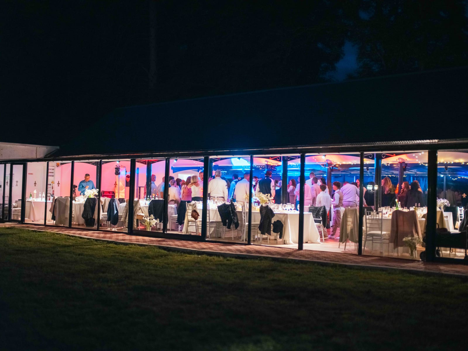 La salle de réception vitrée du Château de Moliens illuminée dans la nuit, vue depuis le parc, mariage au Château de Moliens, par Jean-Baptiste Argyre (Jaysphotography)