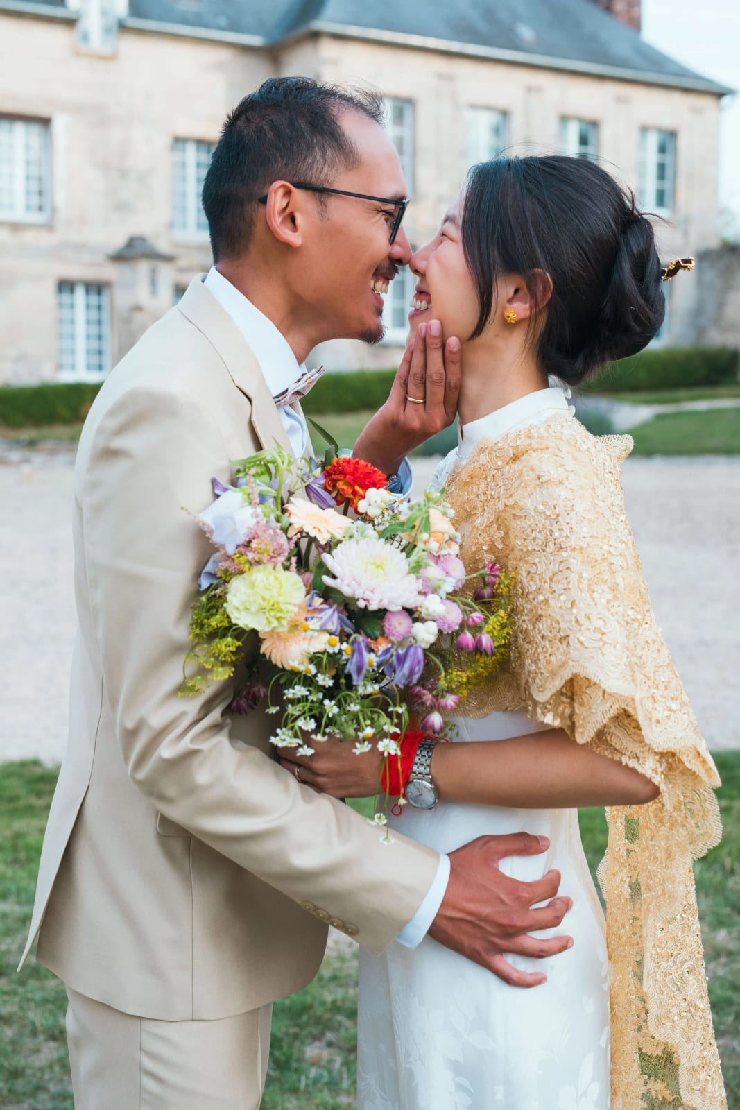 Les mariés nez contre nez, la main de la mariée sur la joue du marié, étole dorée et bouquet coloré, mariage au Domaine de Brion, par Jean-Baptiste Argyre (Jaysphotography)