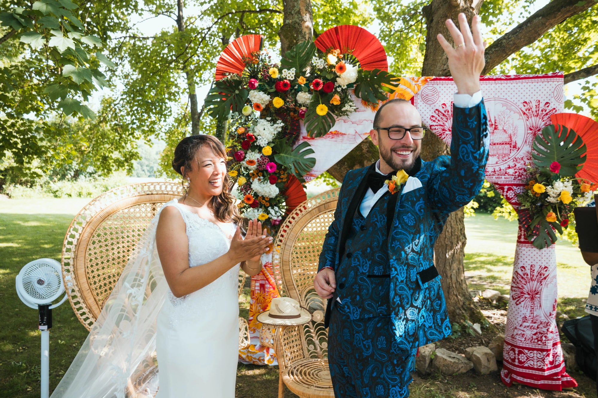 Les mariés saluant leurs invités sous l'arche exotique de la cérémonie, mariage au La Ferme de la Biza, par Jean-Baptiste Argyre (Jaysphotography)