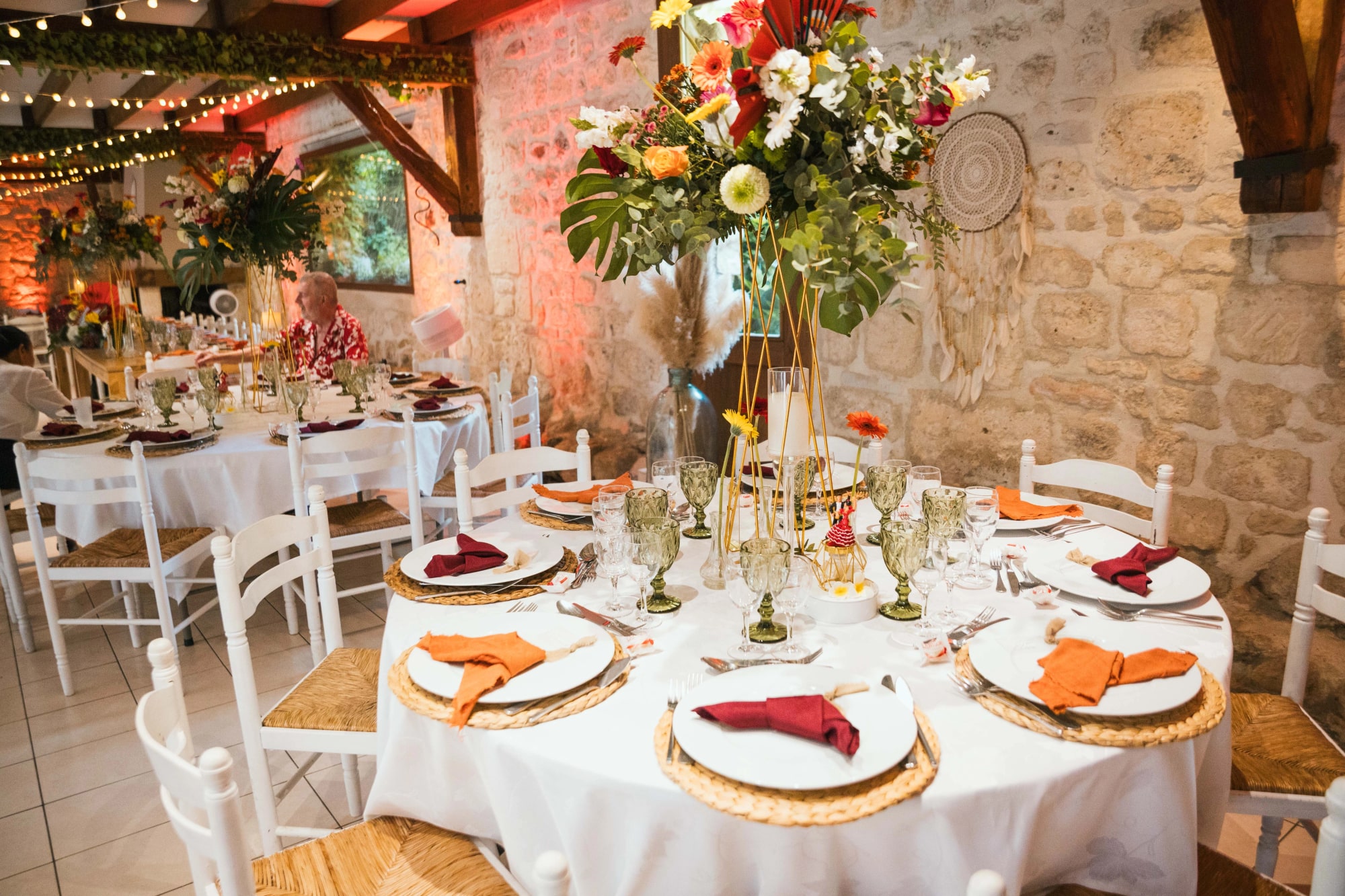 Tables dressées sous les guirlandes de la grange en pierre, mariage au La Ferme de la Biza, par Jean-Baptiste Argyre (Jaysphotography)