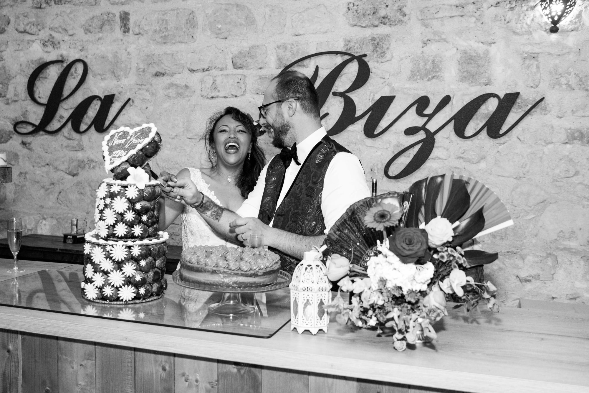 La découpe du gâteau en noir et blanc, éclats de rire des mariés, mariage au La Ferme de la Biza, par Jean-Baptiste Argyre (Jaysphotography)