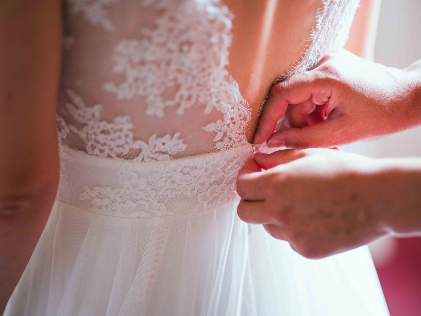 On ferme le dos en dentelle de la robe de mariée, gros plan, mariage au Château de Reilly, par Jean-Baptiste Argyre (Jaysphotography)