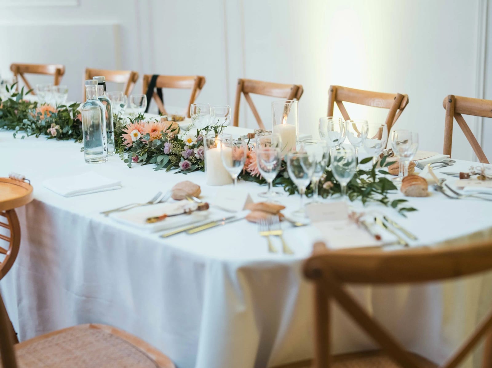 Table dressée au Château de Reilly : chaises de bois à dossier croisé, guirlande de verdure et de fleurs sur nappe blanche, mariage au Château de Reilly, par Jean-Baptiste Argyre (Jaysphotography)