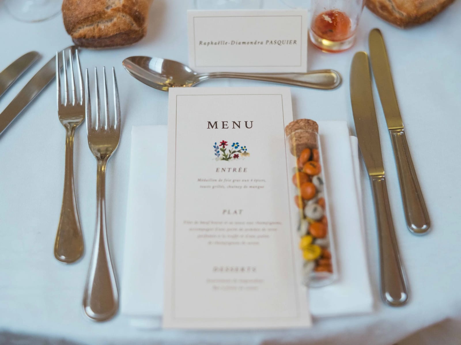 Une place dressée : menu, marque-place au nom de l'invité et tube de dragées colorées, mariage au Château de Reilly, par Jean-Baptiste Argyre (Jaysphotography)