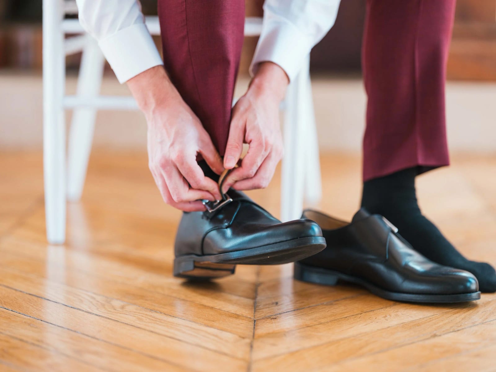 Le marié lace ses souliers noirs sur le parquet d'un salon du Château de Moliens, mariage au Château de Moliens, par Jean-Baptiste Argyre (Jaysphotography)