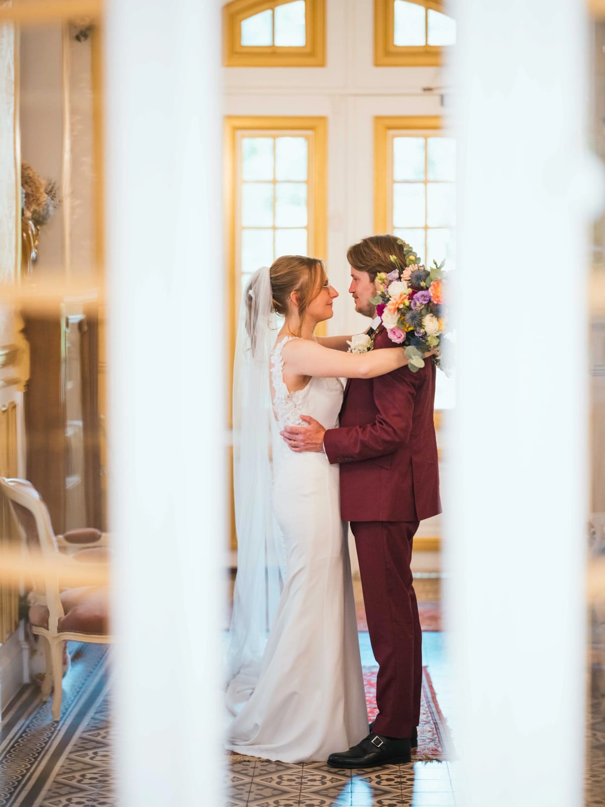 Baiser des mariés avec le bouquet coloré, salon clair du Château de Moliens, mariage au Château de Moliens, par Jean-Baptiste Argyre (Jaysphotography)