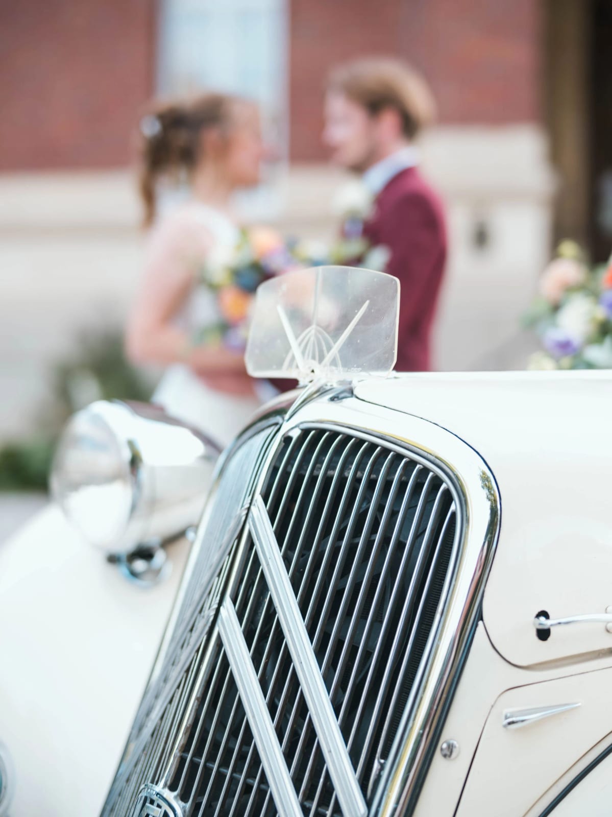 Les mariés flous derrière la calandre d'une Citroën Traction Avant blanche, Château de Moliens, mariage au Château de Moliens, par Jean-Baptiste Argyre (Jaysphotography)