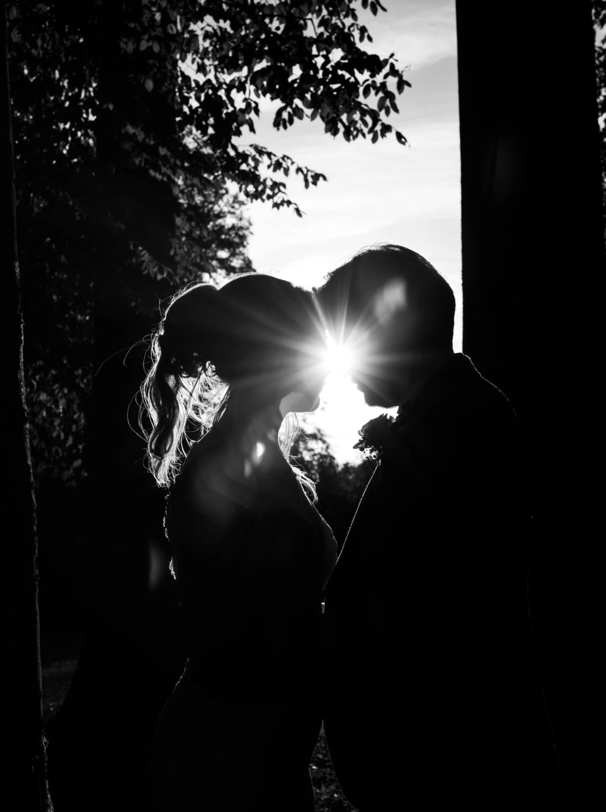 Silhouettes des mariés en noir et blanc à contre-jour dans le parc, soleil en étoile entre les feuilles, mariage au Château de Moliens, par Jean-Baptiste Argyre (Jaysphotography)