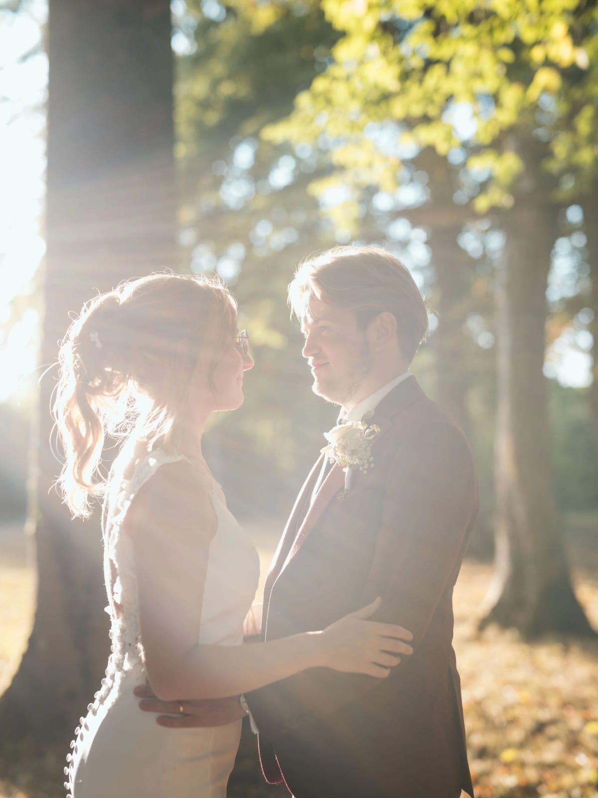 Les mariés enlacés à contre-jour dans la lumière dorée du parc du Château de Moliens, fin de journée d'août, mariage au Château de Moliens, par Jean-Baptiste Argyre (Jaysphotography)