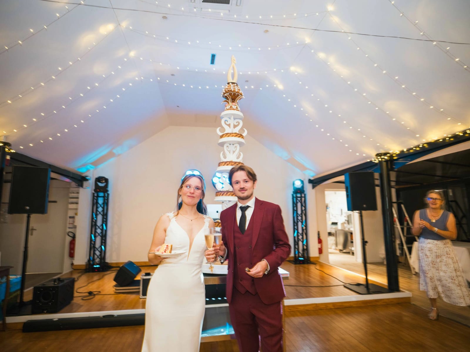 Les mariés une coupe à la main devant la pièce montée qui monte jusque sous la charpente, soirée au Château de Moliens, mariage au Château de Moliens, par Jean-Baptiste Argyre (Jaysphotography)