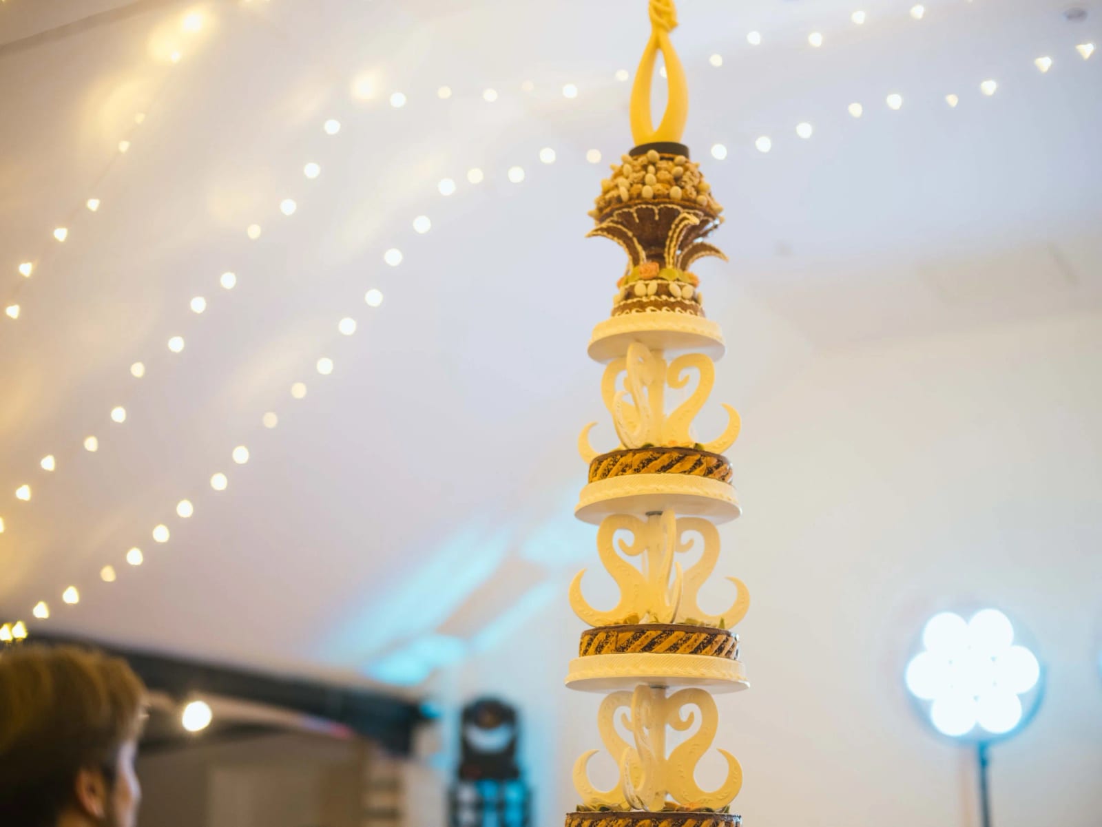 La pièce montée en gros plan : couronnes de choux caramélisés, disques clairs et arabesques de sucre ambré, faite par l'oncle de la mariée, mariage au Château de Moliens, par Jean-Baptiste Argyre (Jaysphotography)
