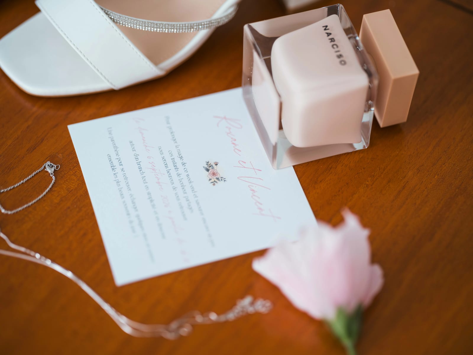 Carte d'invitation au brunch du lendemain, flacon de parfum Narciso, sandale blanche et fleur rose sur une table vernie, mariage au Château de Sainte-Claire, Berneuil-sur-Aisne, par Jean-Baptiste Argyre (Jaysphotography)