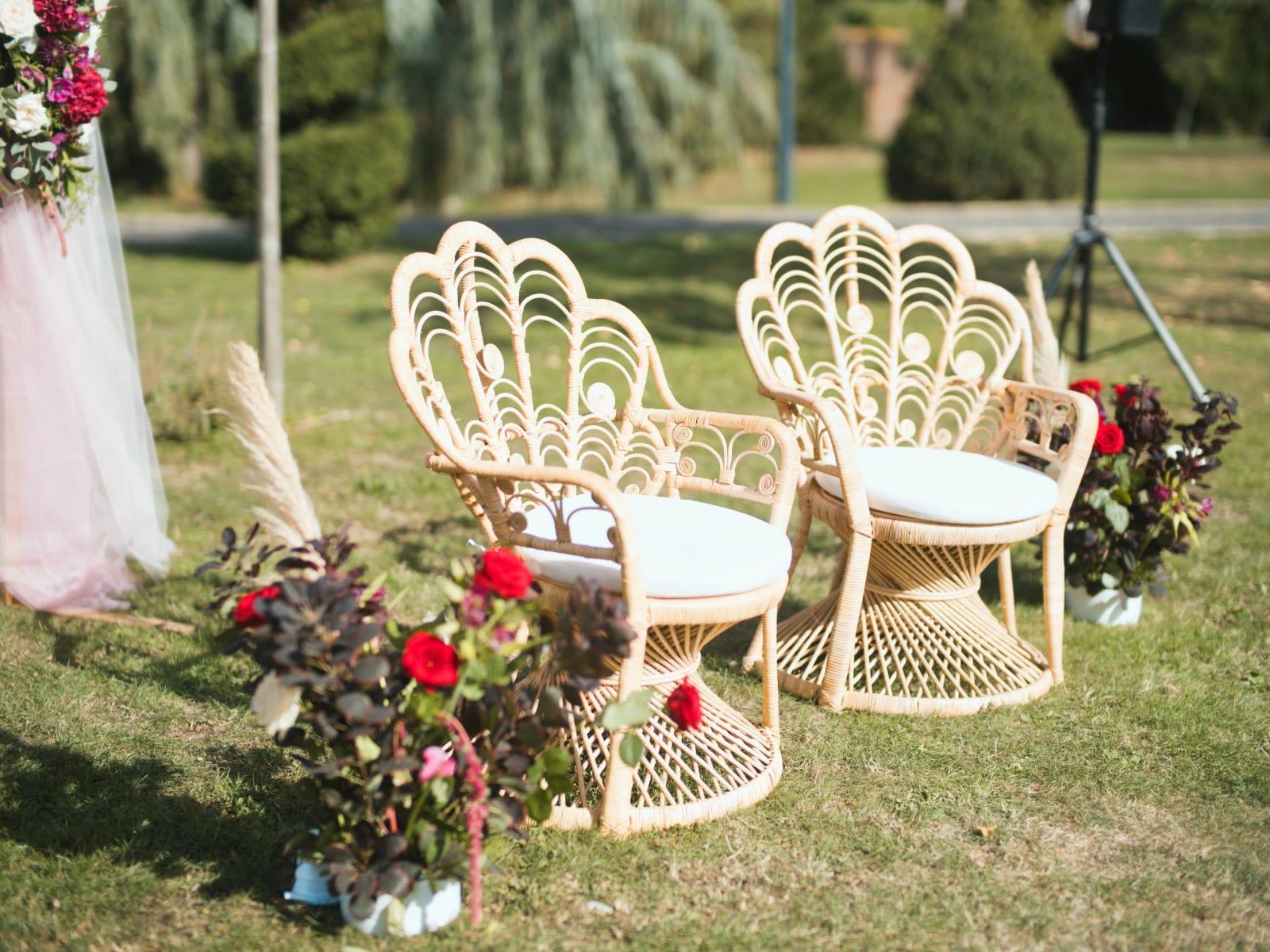 Deux fauteuils en rotin à dossier en éventail et compositions de roses rouges et feuillage pourpre pour la cérémonie laïque au Clos d'Amblaincourt, mariage au Clos d'Amblaincourt, par Jean-Baptiste Argyre (Jaysphotography)