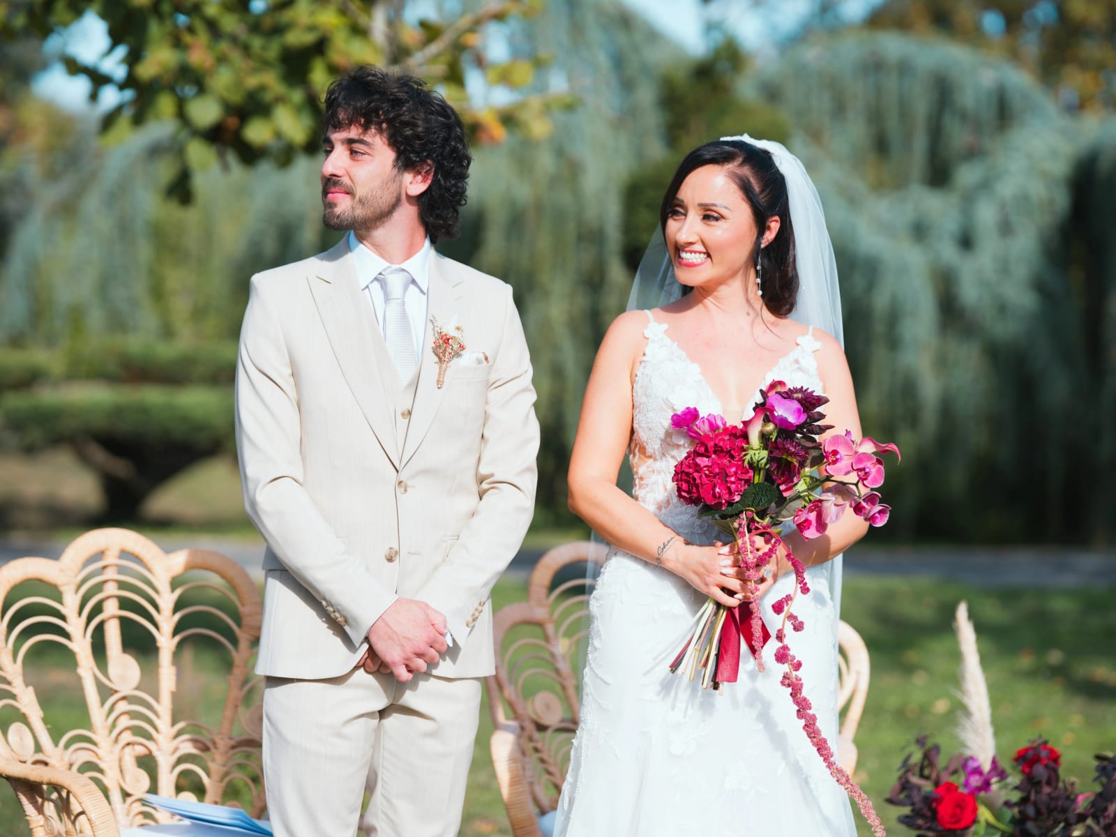 Les mariés côte à côte pendant la cérémonie laïque devant un saule pleureur, bouquet d'hortensia rouge et d'orchidées roses, mariage au Clos d'Amblaincourt, par Jean-Baptiste Argyre (Jaysphotography)