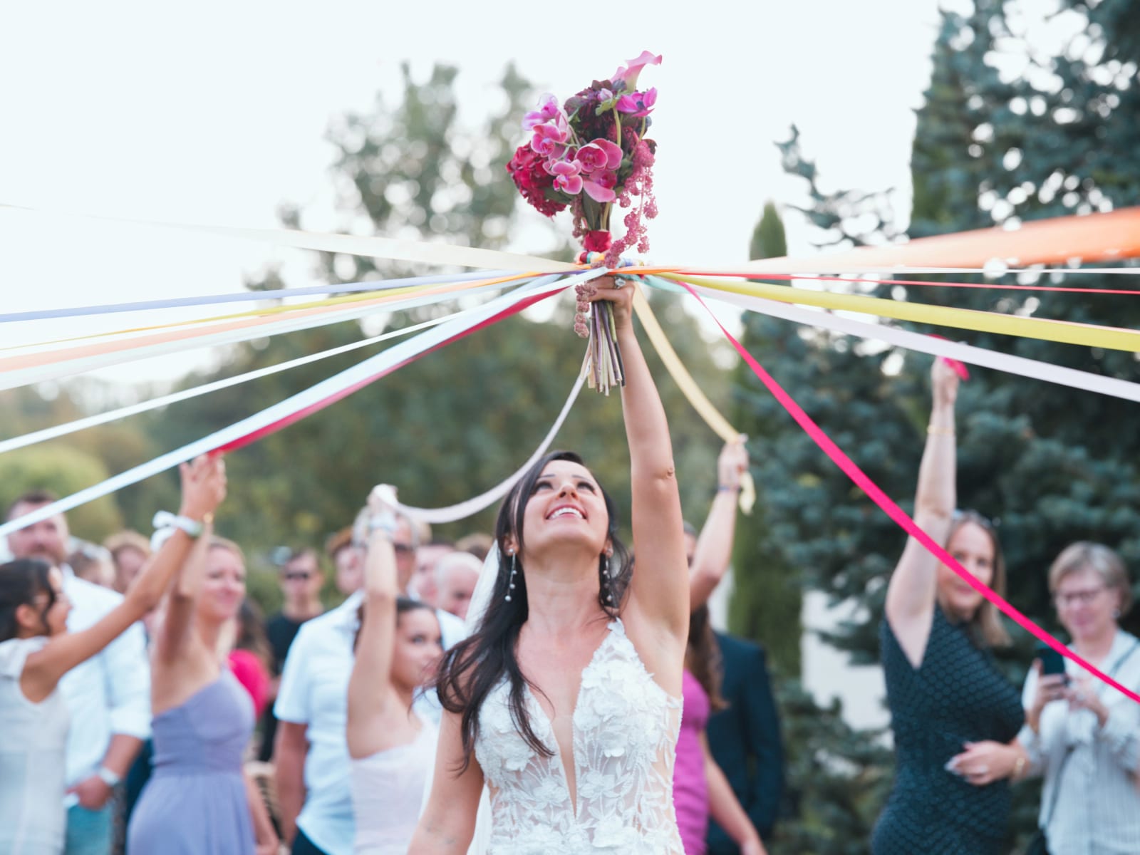 Ronde des rubans : la mariée lève son bouquet au centre de rubans multicolores tenus par les invités, mariage au Clos d'Amblaincourt, par Jean-Baptiste Argyre (Jaysphotography)