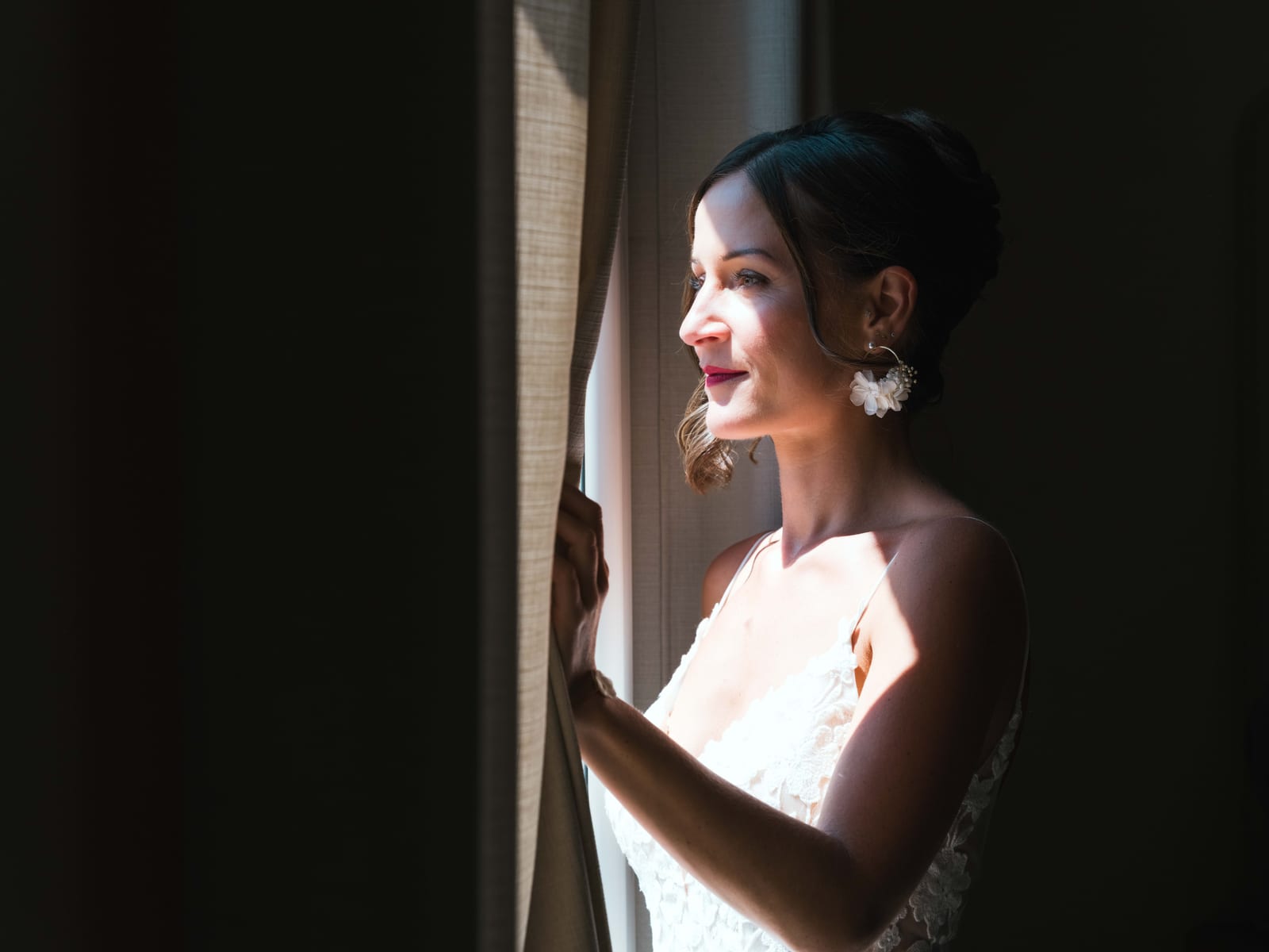 Mathilde lors des préparatifs, regard concentré, lumière naturelle enveloppante depuis la fenêtre du refuge, mariage au Refuges des 3 Ours, par Jean-Baptiste Argyre (Jaysphotography)