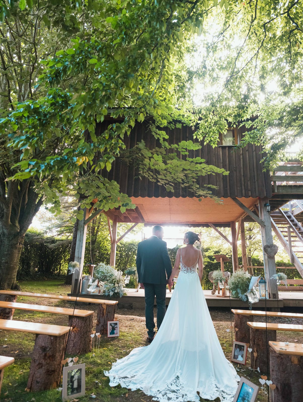 Panneau de cérémonie laïque en bois blanc entouré de fleurs champêtres, installé à l'entrée de l'espace extérieur, mariage au Refuges des 3 Ours, par Jean-Baptiste Argyre (Jaysphotography)