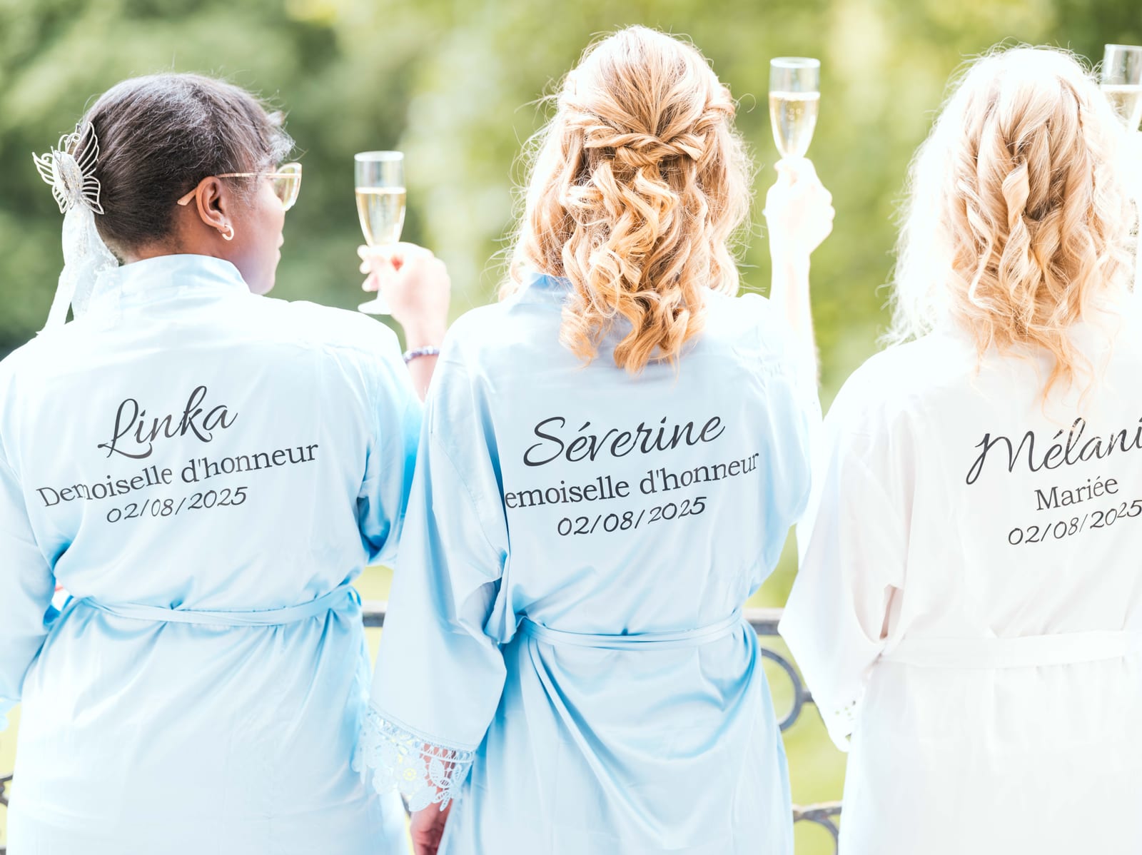 Mélanie et ses témoins en peignoirs personnalisés, coupe de champagne à la main, de dos, mariage au Abbaye de Longpont & Paris, par Jean-Baptiste Argyre (Jaysphotography)