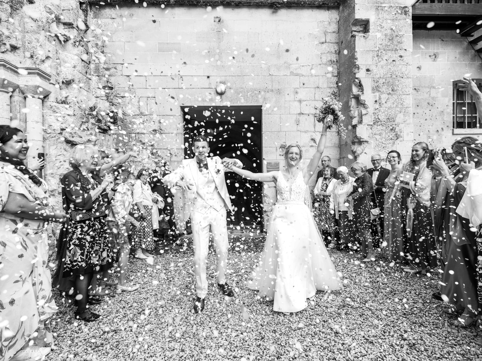 Sortie sous une pluie de pétales, en noir et blanc, mariage au Abbaye de Longpont & Paris, par Jean-Baptiste Argyre (Jaysphotography)