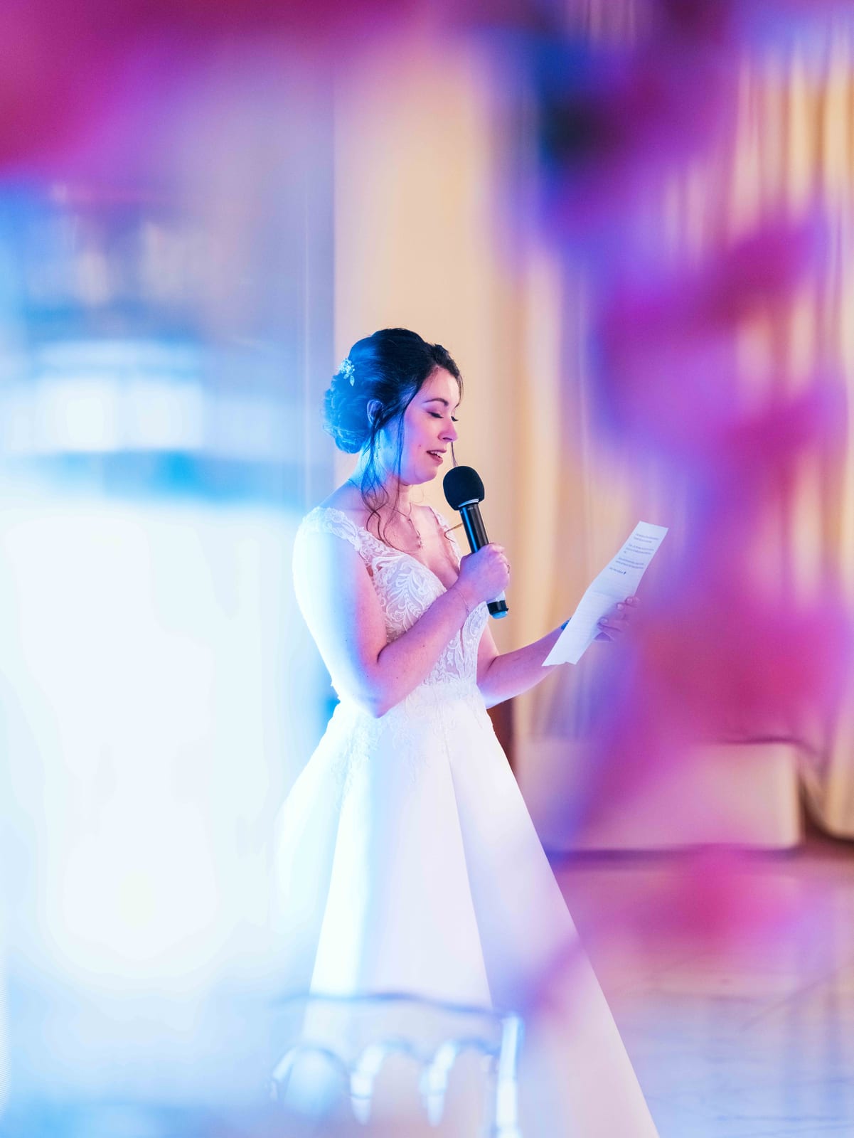 Mélissa au micro sous un éclairage violet et rose dans la salle de réception, mariage au Domaine de la Muette, par Jean-Baptiste Argyre (Jaysphotography)
